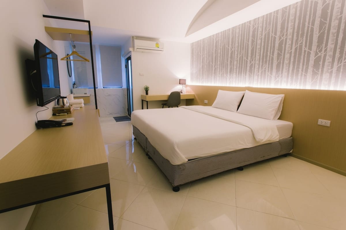 A hotel room with a bed, a desk, a TV, and a mirror.