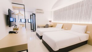 A modern hotel room with two beds, a desk, a TV, and a mirror. - Royal Princess City (Lamphun)