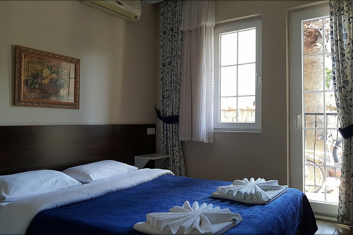 Una habitación de hotel con una cama grande, un cuadro en la pared y una ventana con cortinas.