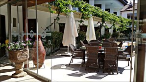 An outdoor seating area with wicker furniture, potted plants, and umbrellas. - Eon Dalyan Boutique Hotel (Ortaca)
