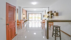 A spacious room with a dining area, a kitchen counter, and a sliding glass door leading to an outdoor area. - Baan Hauen Inn (Chiang Mai)