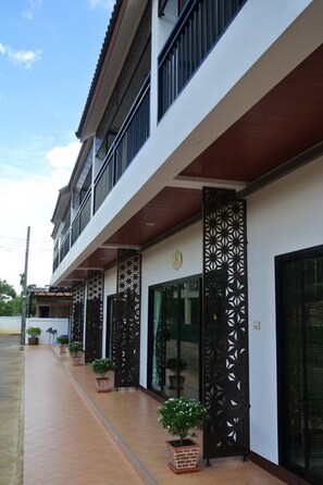 A modern building with a covered walkway, potted plants, and a decorative metal fence. - Baan Hauen Inn (Chiang Mai)