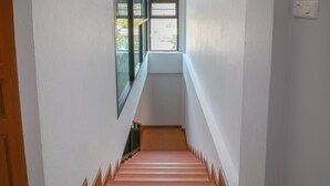 A narrow stairway with wooden steps and a glass door at the top. - Baan Hauen Inn (Chiang Mai)