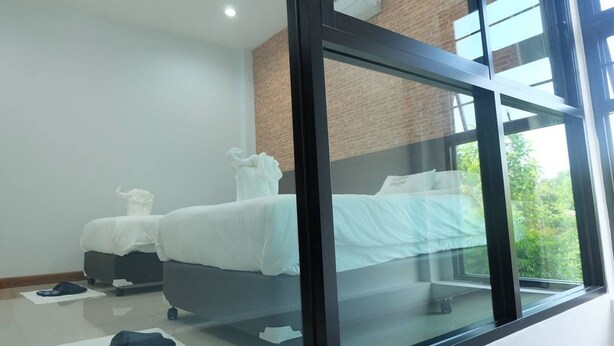 A modern bedroom with a large window, a bed, a small table, and a chair. - Baan Hauen Inn (Chiang Mai)