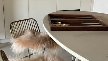 A modern kitchen with white cabinets, a round dining table, and a fur-covered chair.