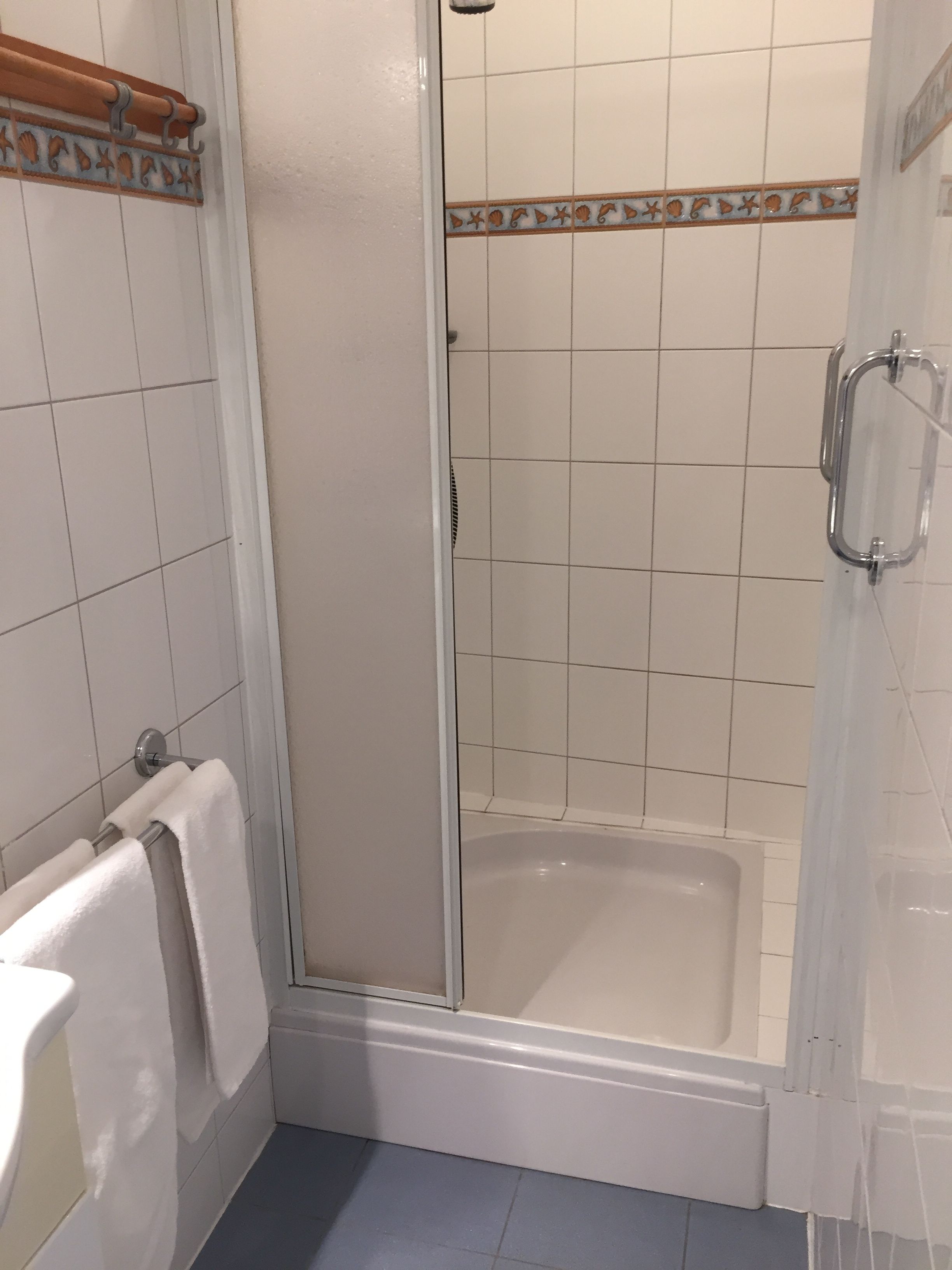 Et badeværelse med bruseniche, badekar og håndklædetørre.