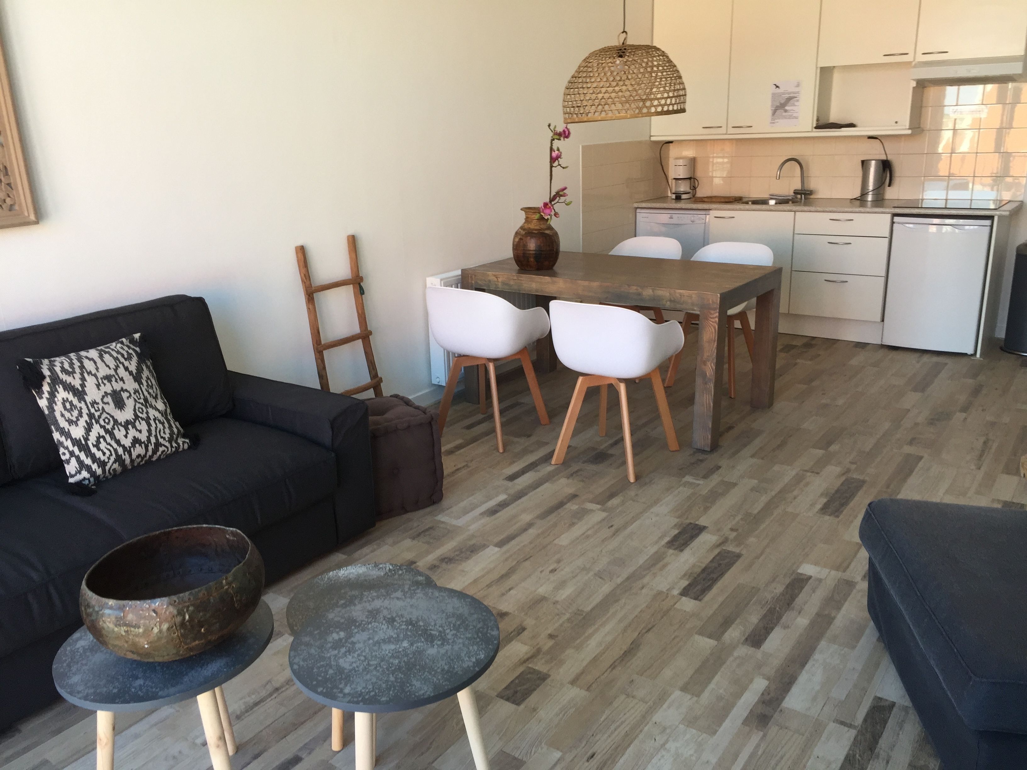 Una sala de estar moderna con un sofá, una mesa de centro y un comedor con mesa y sillas de madera.