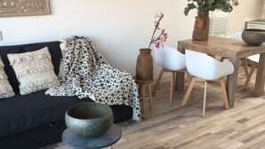 Un salon moderne avec un canapé noir, un plaid à motifs et une table basse sur laquelle sont empilés des bols.