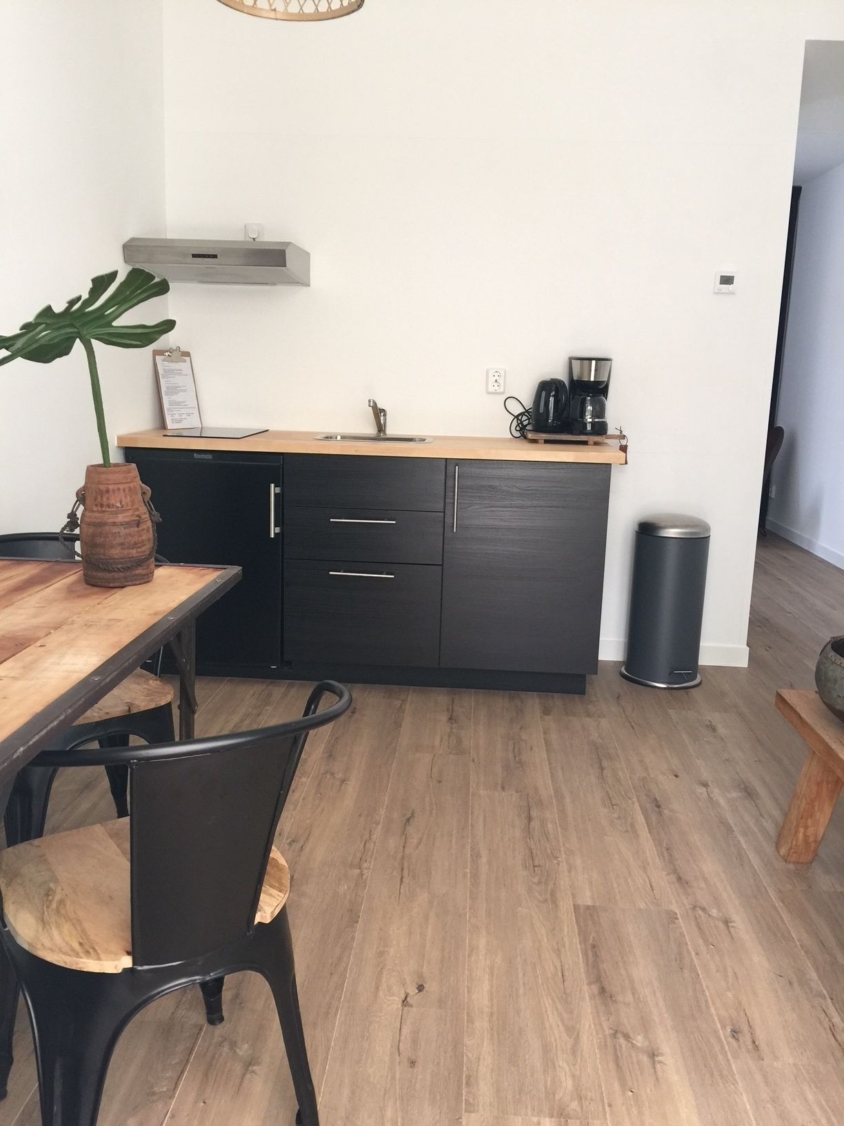 Une cuisine moderne avec un plan de travail en bois, des meubles de rangement noirs, un évier et une machine à café.