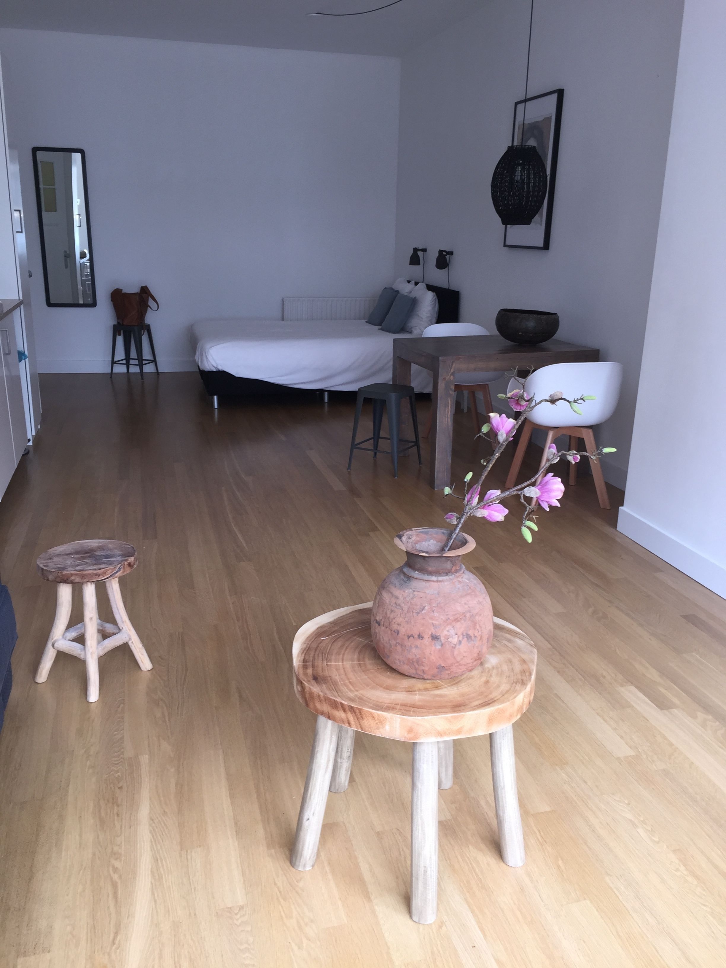Et moderne soveværelse med en seng, et natbord og en vase med blomster på en træskammel.