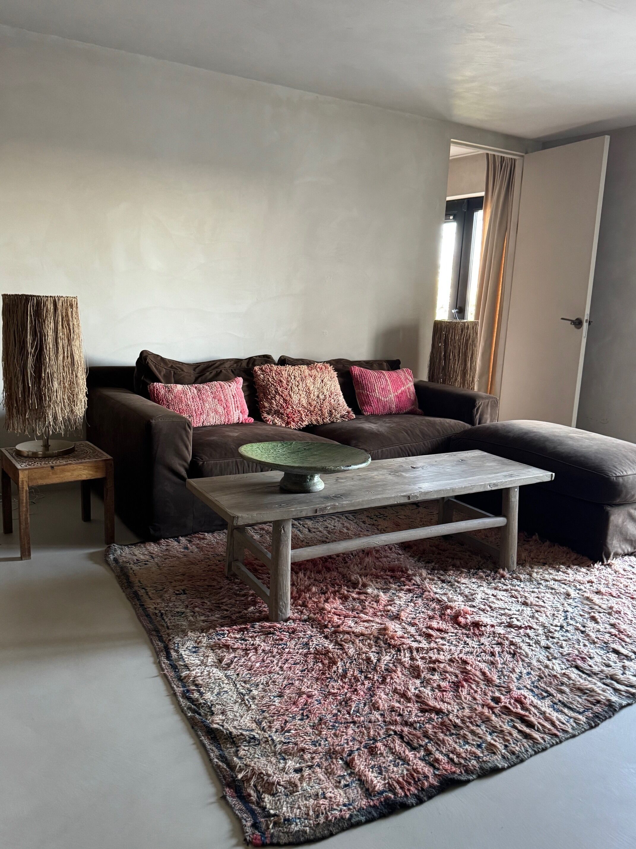 A living room with a brown sofa, a wooden coffee table, and a patterned rug.