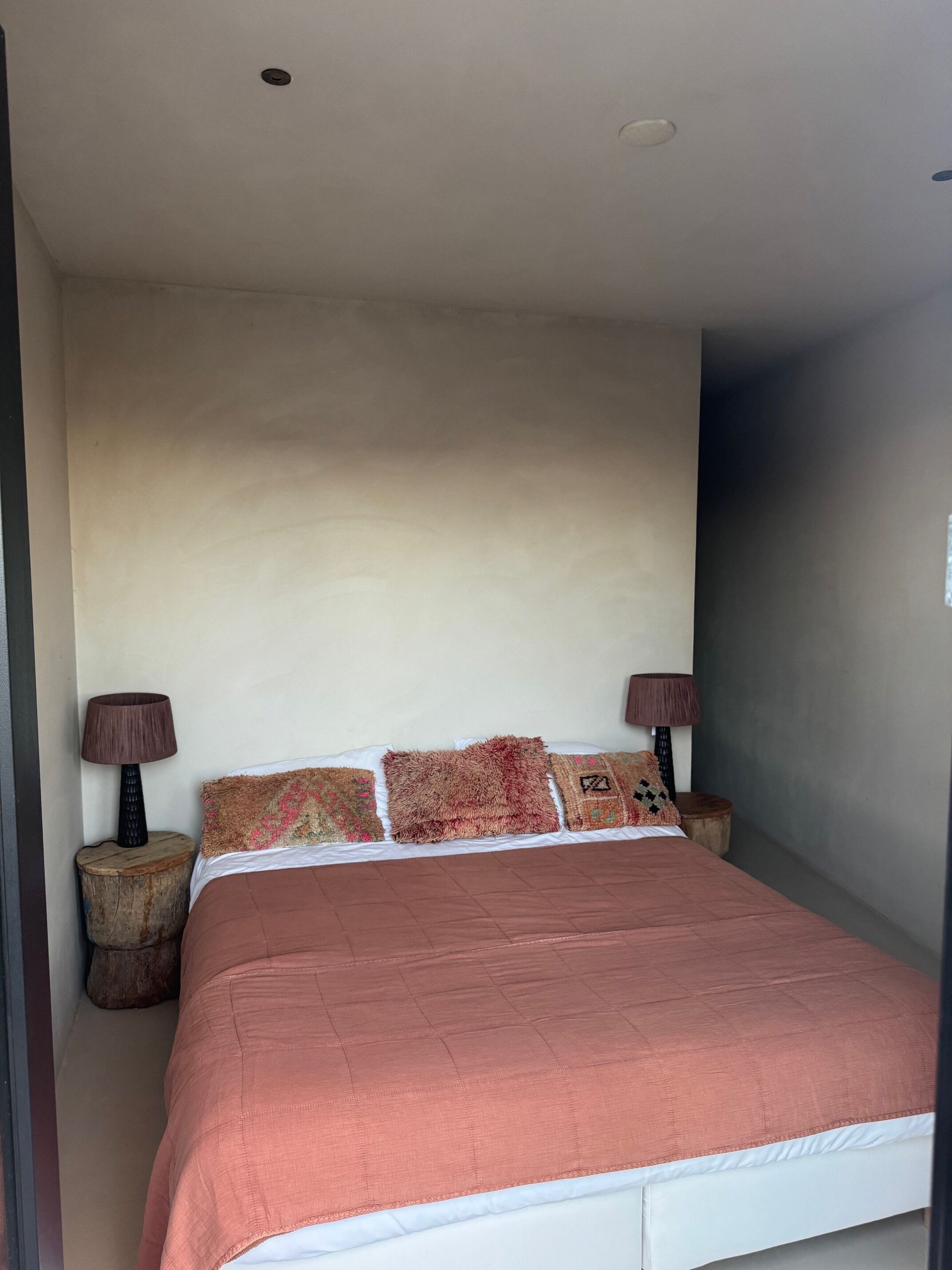 A bedroom with a large bed, two bedside tables with lamps, and a plain wall.