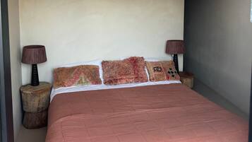 A bedroom with a large bed, two bedside tables with lamps, and a plain wall.