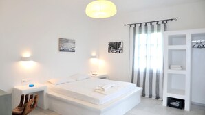 A modern bedroom with a large bed, bedside lamps, a wardrobe, and a hanging light fixture. - Helios Beach Studios (Naxos)