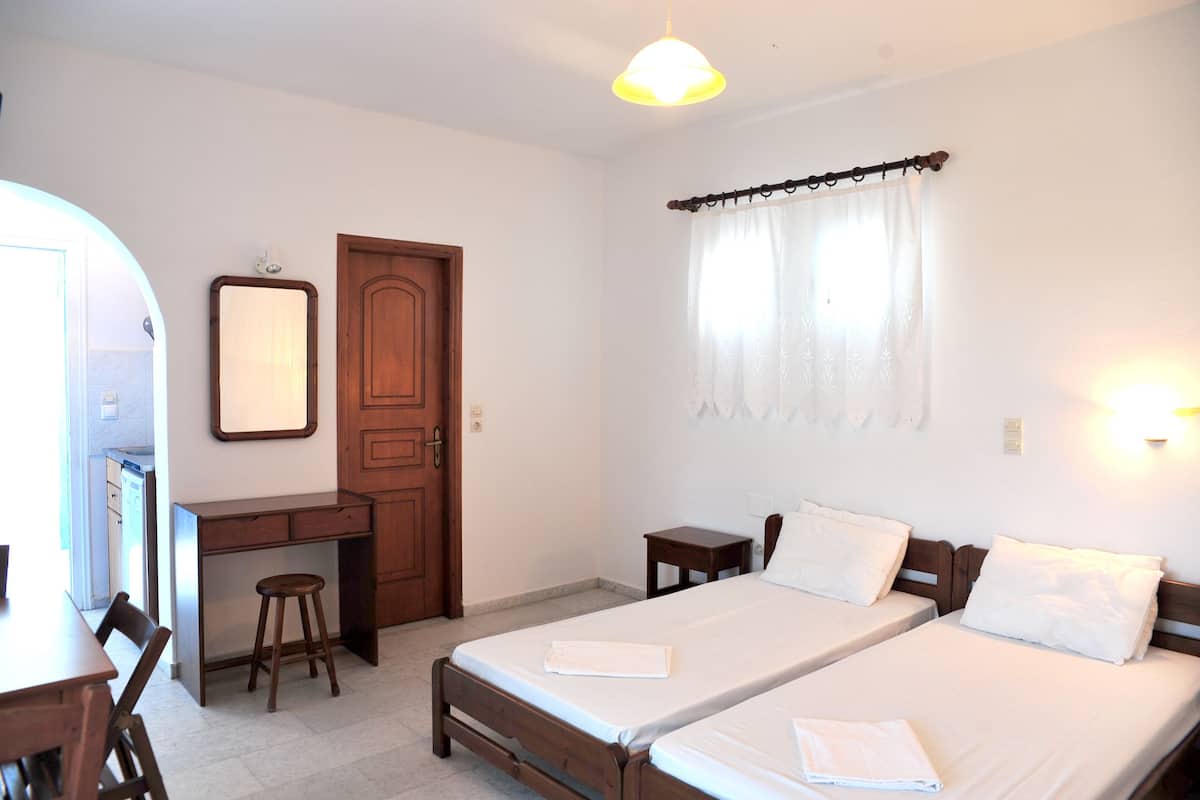 A bedroom with two single beds, a desk, and a chair.