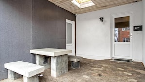 Un patio con un banco de hormigón, una puerta y una ventana pequeña.