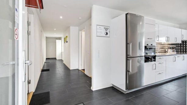 Una cocina moderna con armarios blancos, un refrigerador de acero inoxidable y un piso de baldosas negras.