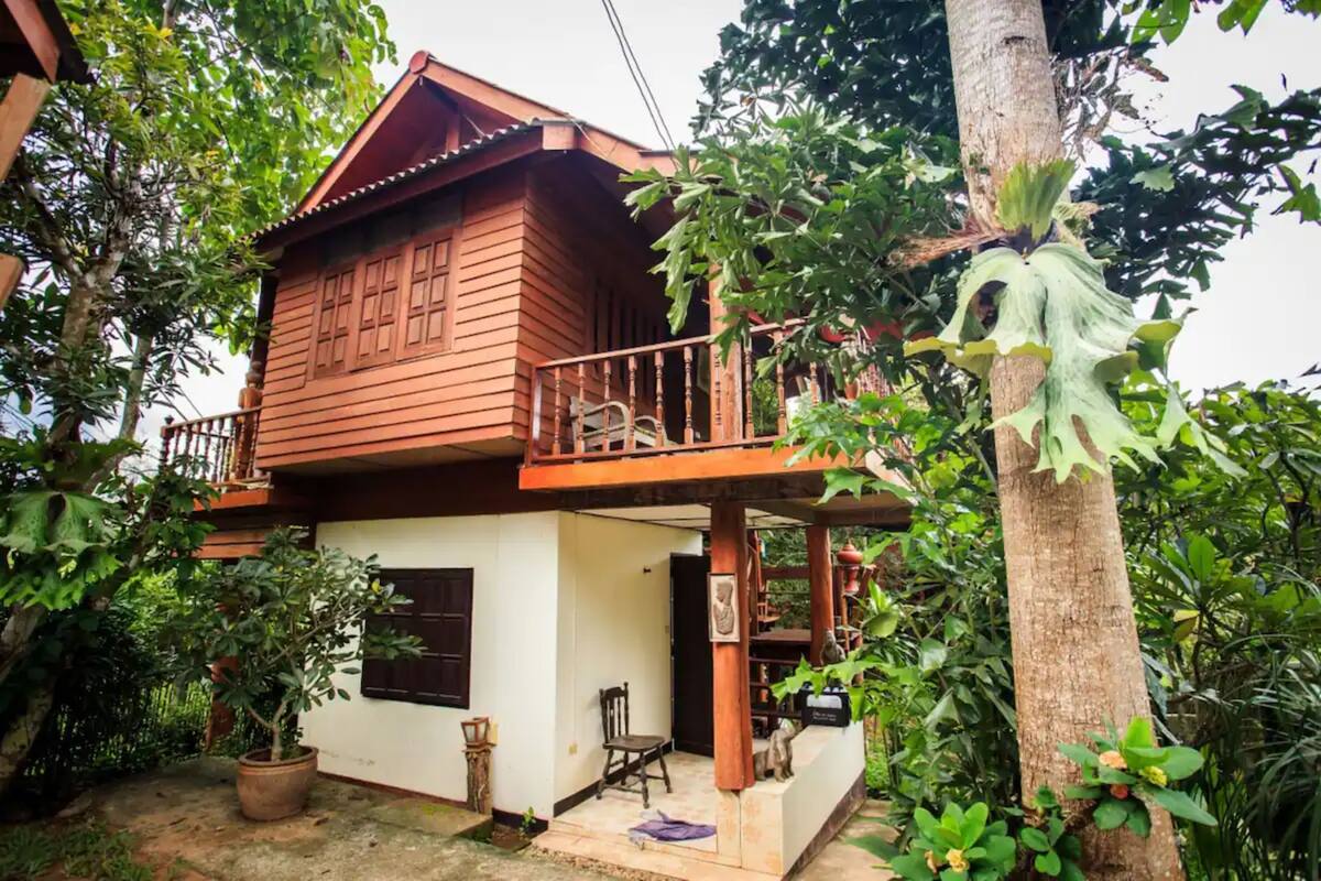 Una casa de madera con balcón, rodeada de vegetación.