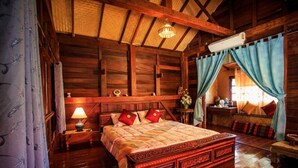 Una habitación de madera con una cama, una mesita de noche, una lámpara y una ventana con cortinas.