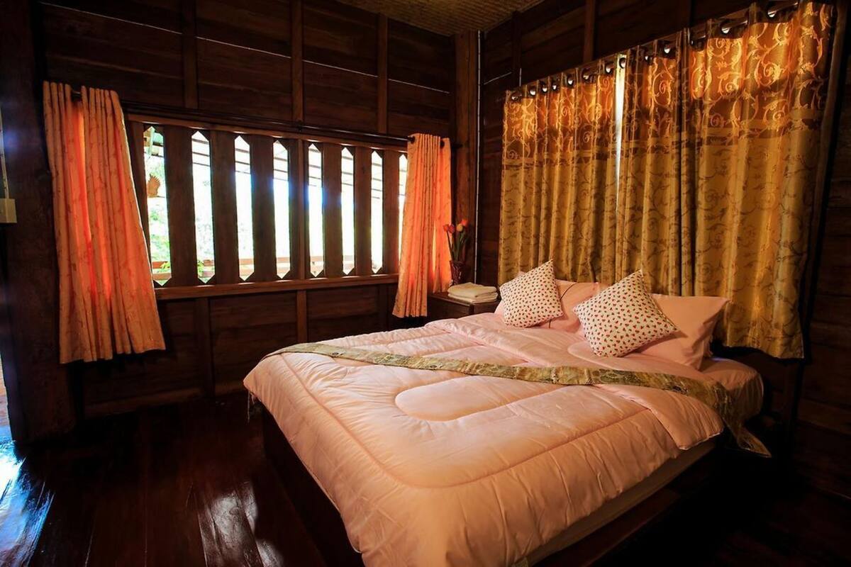 Una habitación de madera con cama, cortinas y una ventana.