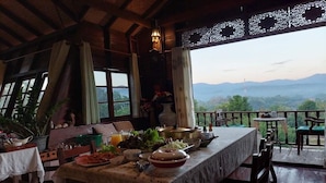 Comedor con mesa lista para comer, con vistas a un paisaje montañoso.