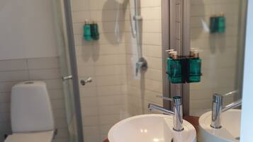 Un baño con lavamanos blanco, espejo y zona de ducha.