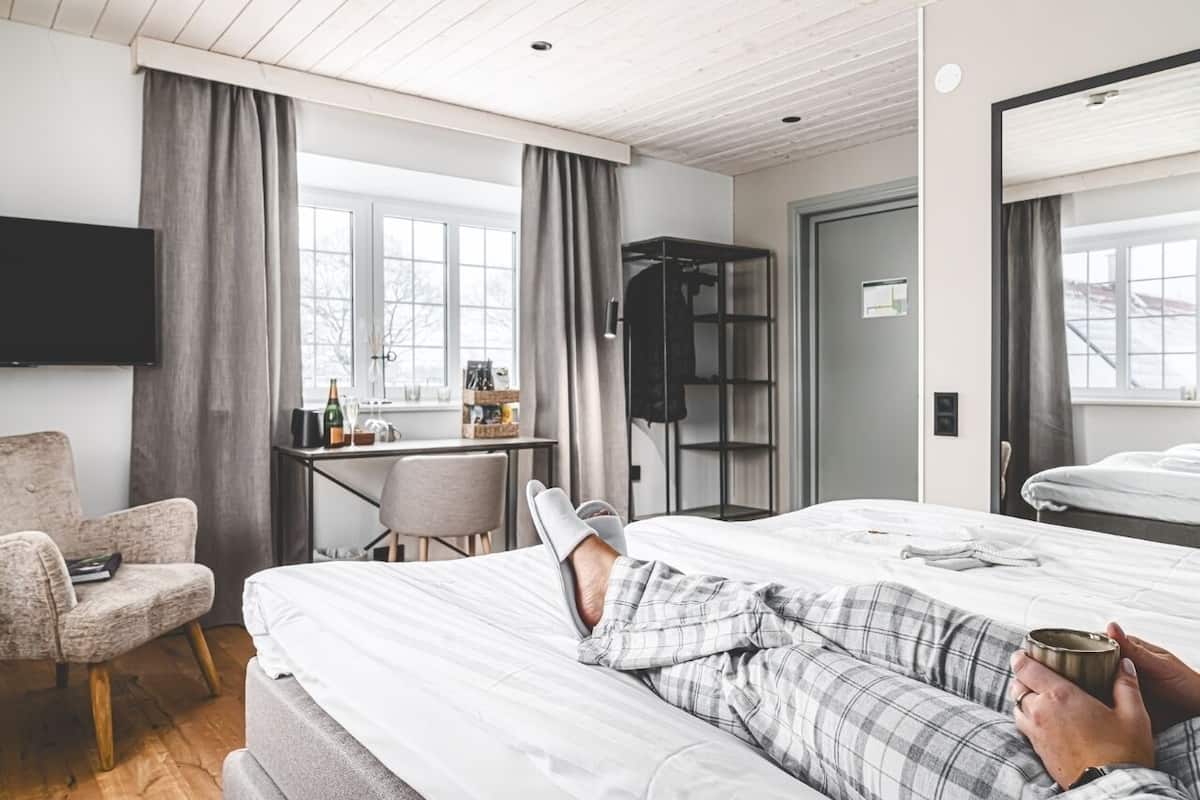 A hotel room with a bed, a desk, a chair, and a TV.