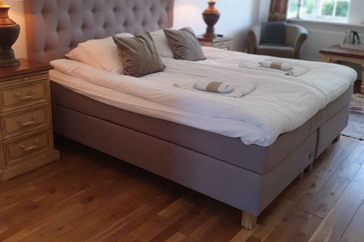 A large bed with a tufted headboard, wooden nightstands, and a lamp on each side.