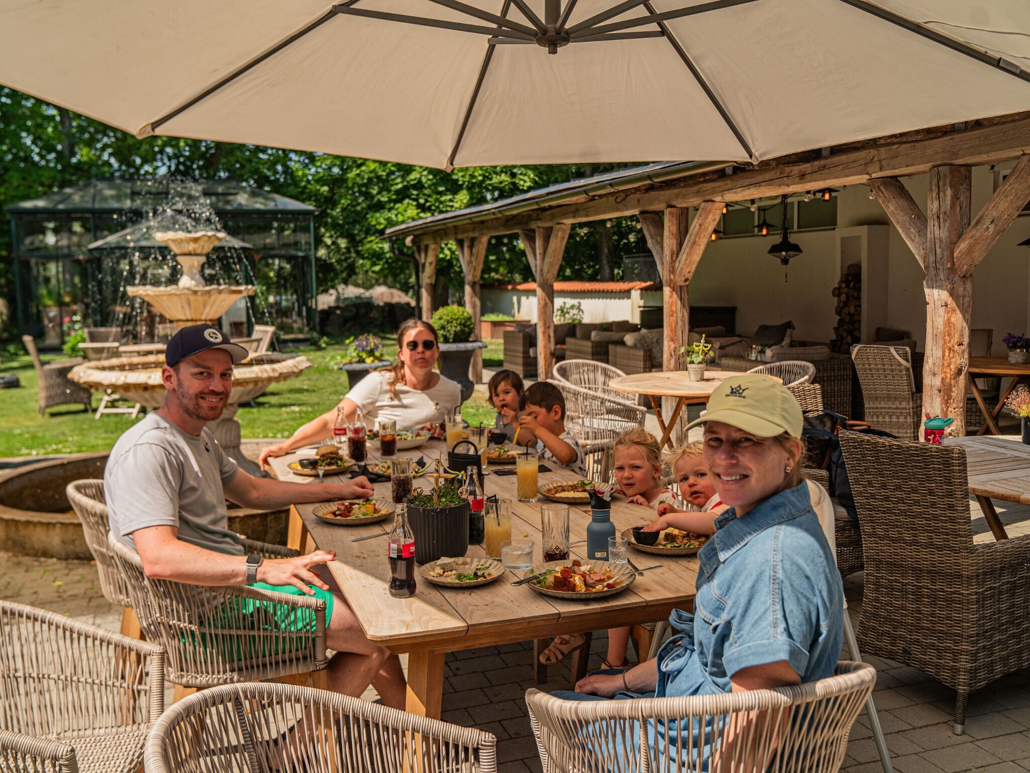 Un espacio de comedor al aire libre con mobiliario de mimbre y una sombrilla grande.
