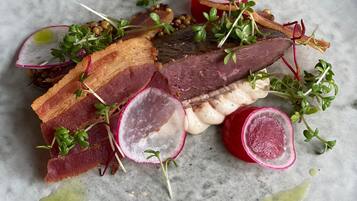 Un plato con diversas carnes y verduras sobre una superficie de mármol.