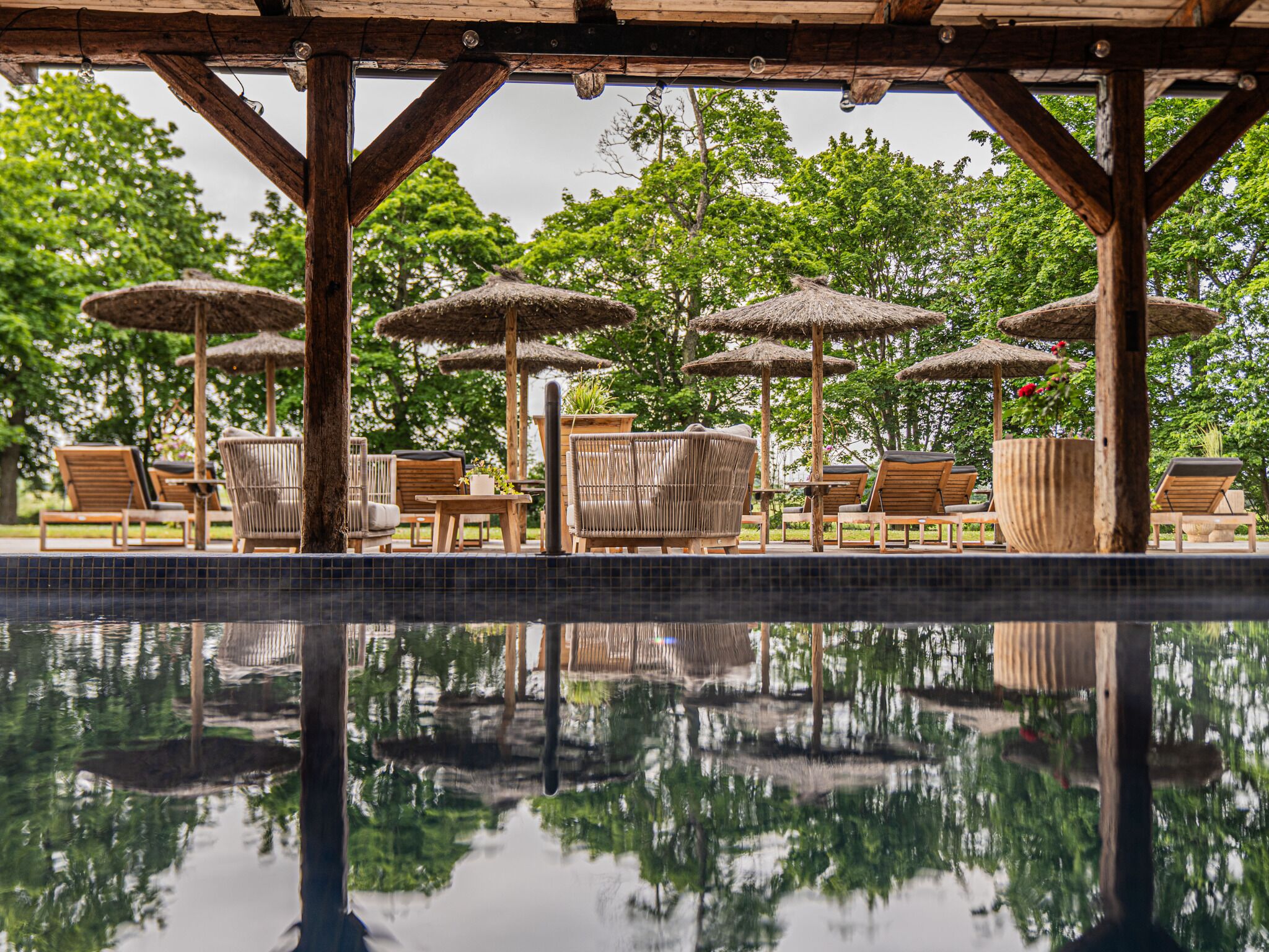 A poolside area with lounge chairs, umbrellas, and a wooden pergola structure.