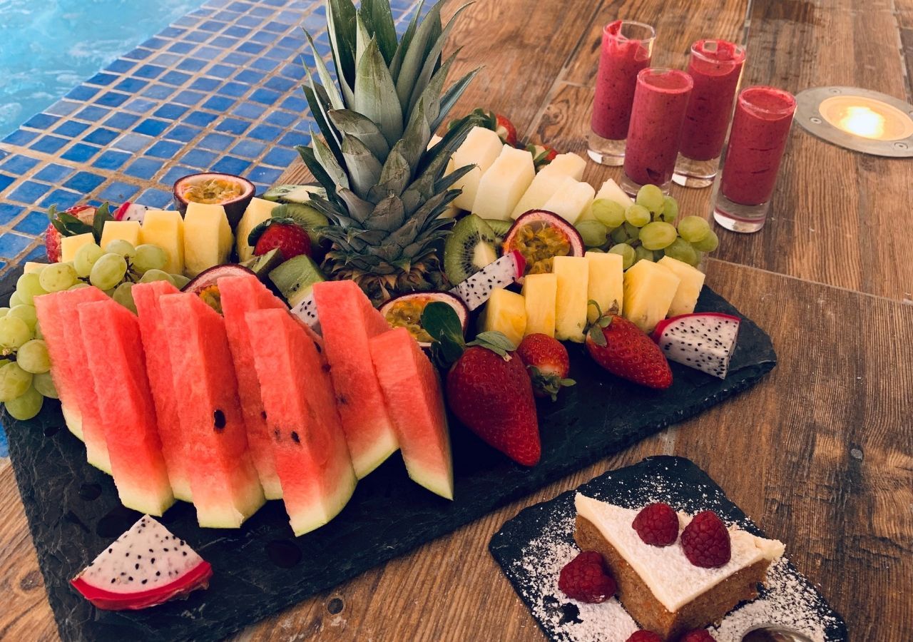 A fruit platter with various fruits and a dessert on a wooden table.