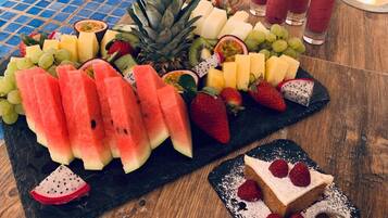 A fruit platter with various fruits and a dessert on a wooden table.