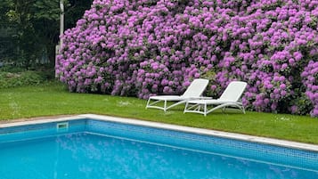 Una piscina al aire libre de temporada, tumbonas
