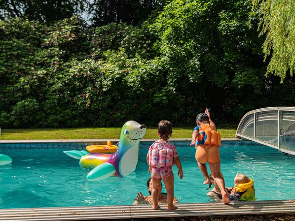 Una piscina con juguetes inflables y gente alrededor.