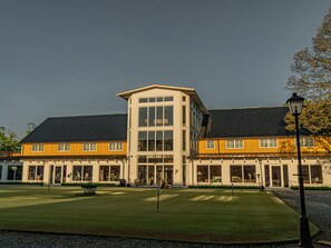 A modern building with a central tower, large windows, and a well-maintained lawn.
