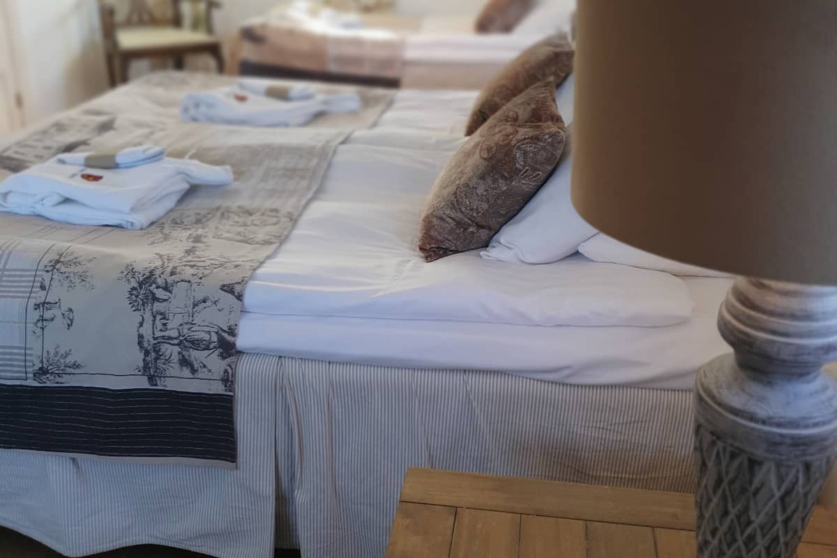 A hotel room with two beds, a wooden table, and a lamp.