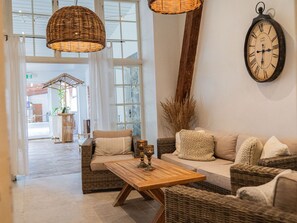 A modern interior with wicker furniture, a wooden coffee table, and a wall-mounted clock. - Elisefarm (Hoor)
