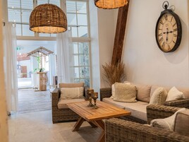 Un interior moderno con muebles de mimbre, una mesa de centro de madera y un reloj montado en la pared.