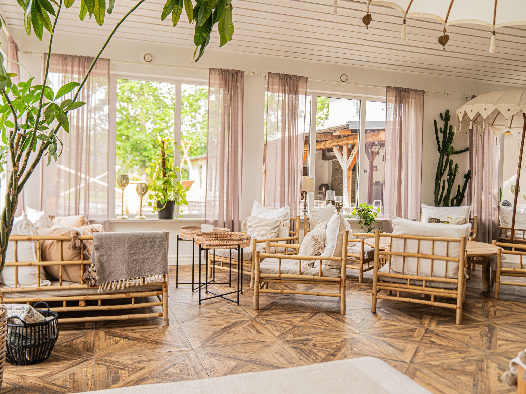 A room with bamboo furniture, a large potted plant, and a view of the outdoors.