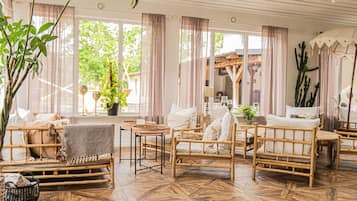 A room with bamboo furniture, a large potted plant, and a view of the outdoors.