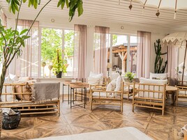 Una habitación con muebles de bambú, una planta grande en maceta y vistas al exterior.