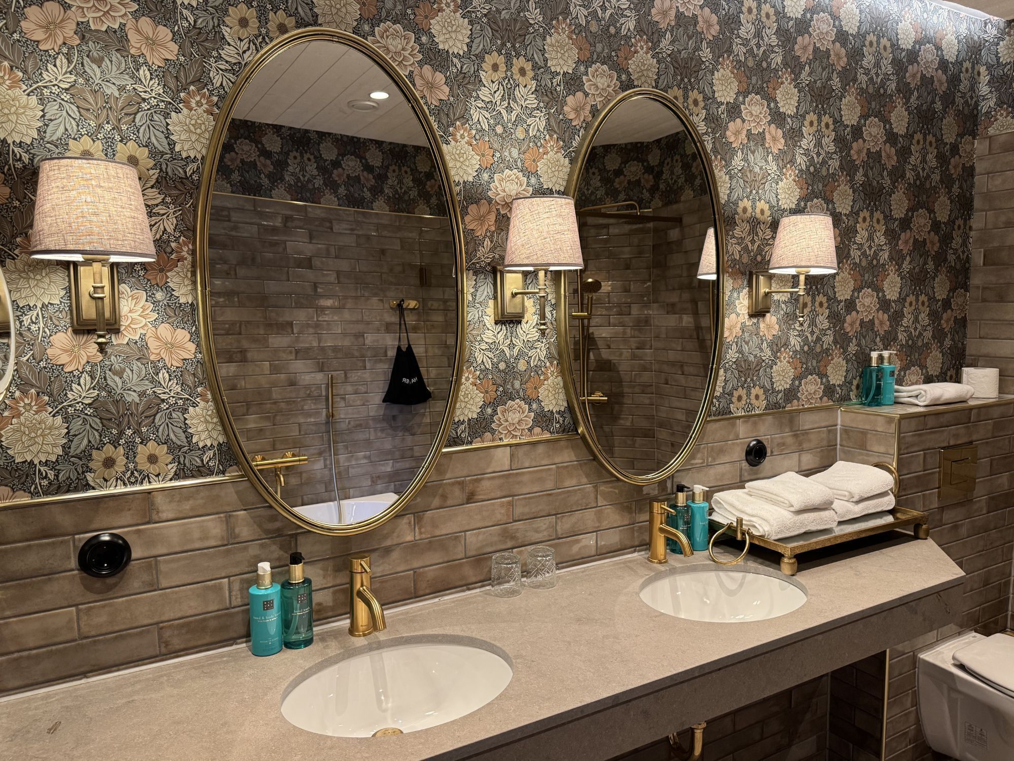 A bathroom with two sinks, a large mirror, and a shower.