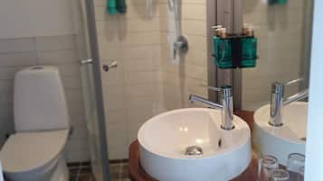 Ein Badezimmer mit Toilette, Waschbecken mit Spiegel und Duschbereich.