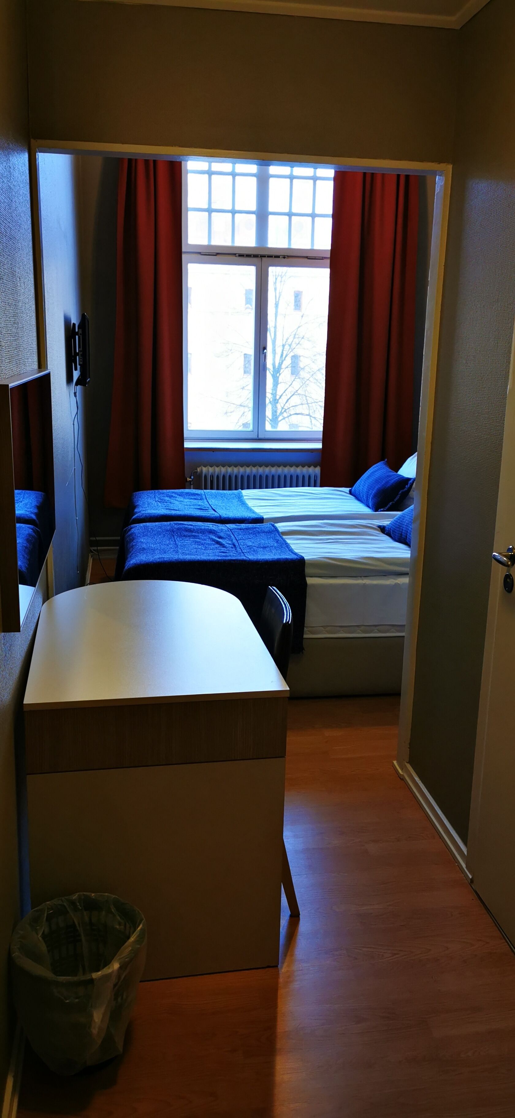 A compact room with a bed, a desk, and a radiator.