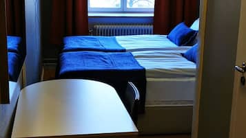A compact room with a bed, a desk, and a radiator.