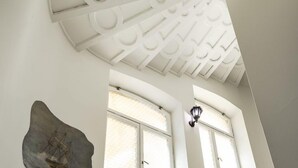 Un escalier orné d’un tableau représentant un navire sur le mur, de grandes fenêtres et un plafond décoratif.