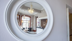 Un miroir rond qui reflète une pièce comprenant un lustre, un coin repas et une cuisine.