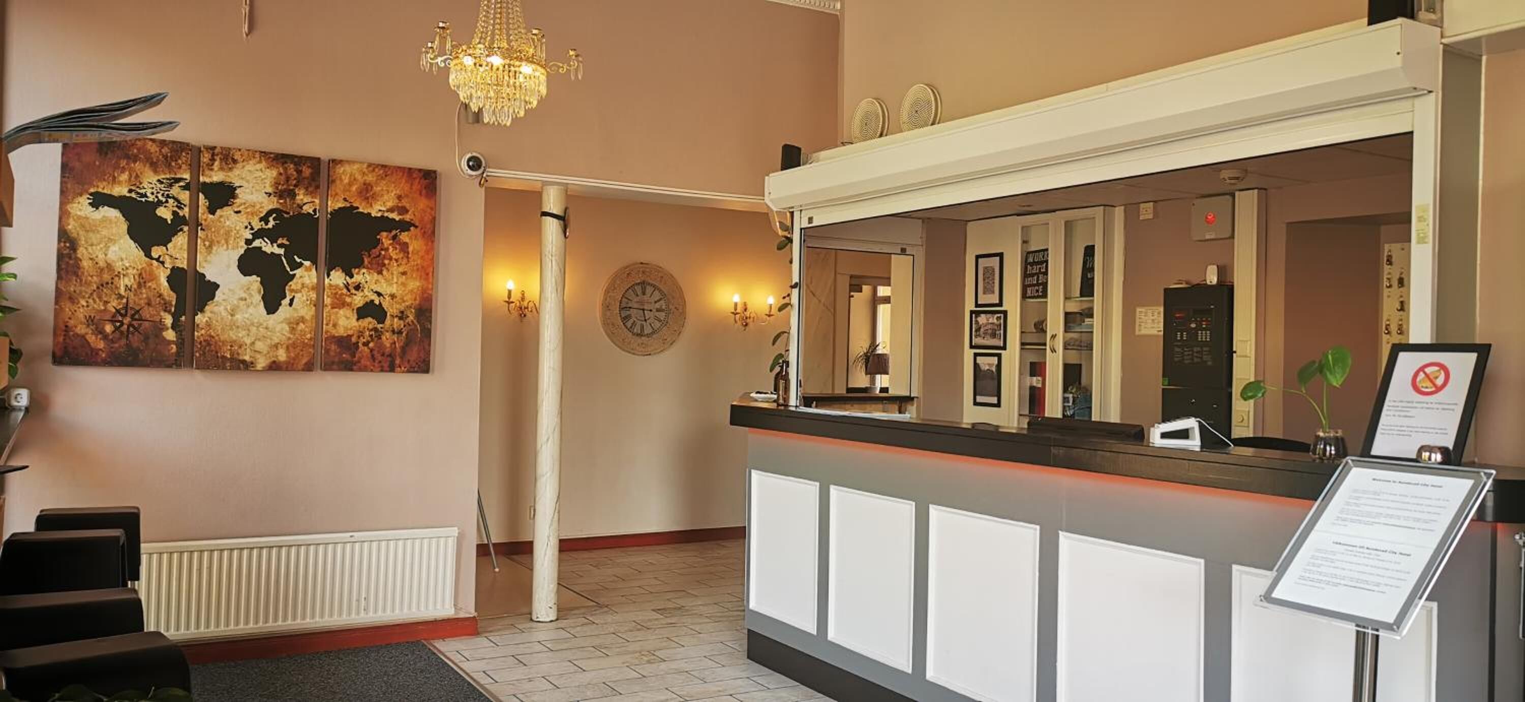 A reception area with a world map artwork, a chandelier, a reception desk, and a signboard.