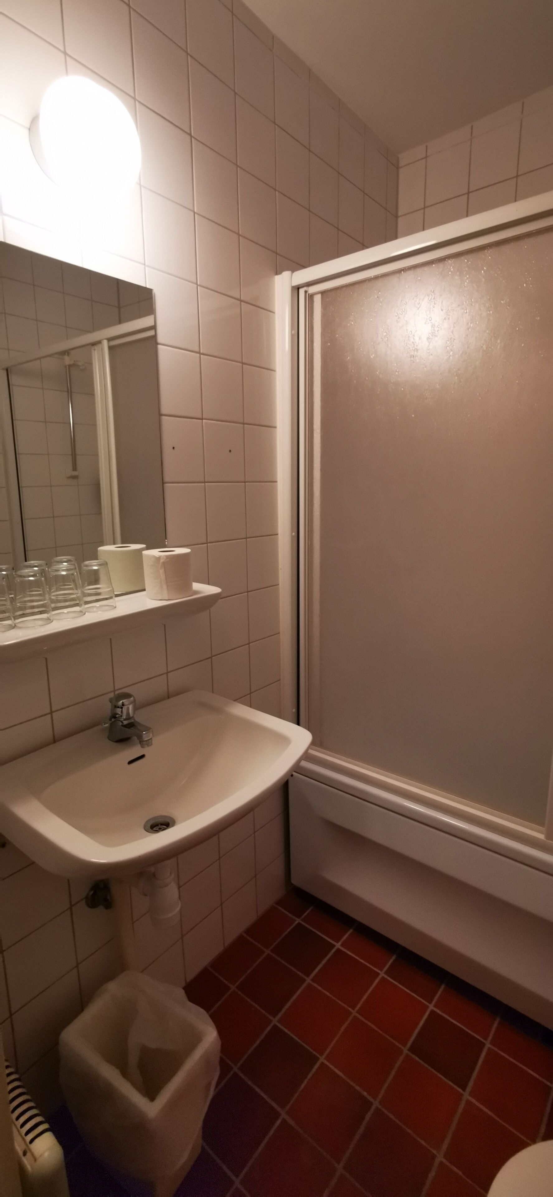 A bathroom with a sink, mirror, and shower.